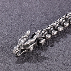 Macro della fibbia a testa di drago e catena a maglie d'osso su bracciale in acciaio
