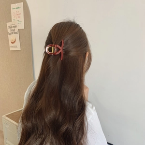 Detail of a large matte burgundy hair claw clip styled on a model in a minimal setting