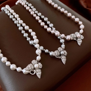 Détail de colliers de perles blanches, gris argenté et roses avec fermoirs à fleurs en zircon