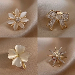 Macro detail of four flower and heart shaped opal brooches on champagne silk