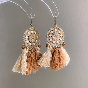 Macro detail of Bohemian tassel earrings with enamel flower charms and wooden beads