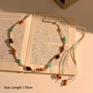 Détail d'une chaîne de taille boho de 170cm avec perles en bois et coquillages