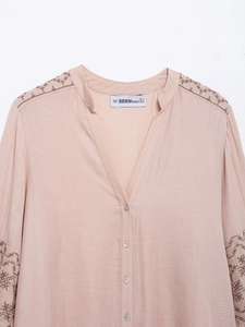 Detail view of V-neck beige blouse showing floral embroidery and collar size label