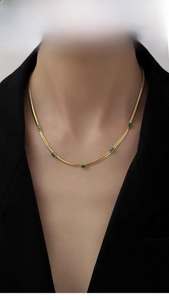 Dettaglio di una collana a catena serpente dorata con cinque zirconi verde smeraldo