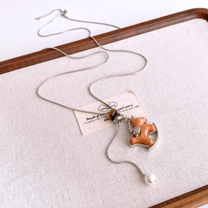 Detailed close-up of woven rocking horse pendant with tiger eye bead and pearl detail