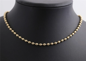 Collier à billes dorées facettées minimaliste présenté sur un buste de mannequin noir