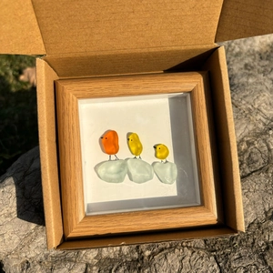 Détail d'oiseaux en verre de mer dans un cadre en bois dans une boîte cadeau brune