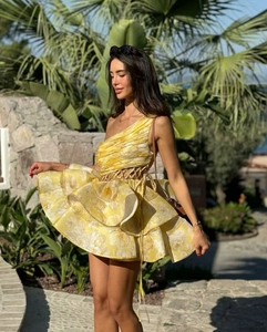 Detail of yellow floral one-shoulder dress with ruffle hem in a tropical outdoor setting