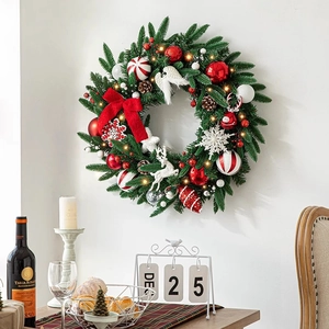Couronne de Noël 50cm avec lumières LED, nœuds rouges et rennes sur un mur blanc
