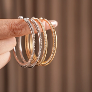 Dettaglio di eleganti orecchini a cerchio intrecciati oro e argento con piccoli cristalli