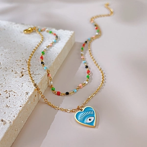Detail of a vintage gold heart evil eye pendant necklace on a natural white stone base