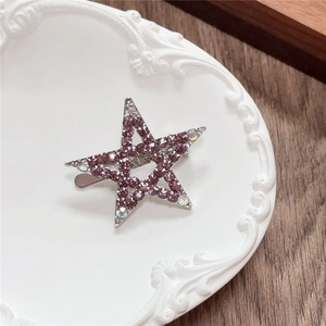 Detailed view of Y2K star-shaped hair clip with pink rhinestones on a white plate