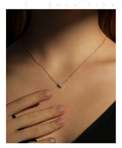 Close-up of heart-shaped silver necklace with zircon stone worn on the neck
