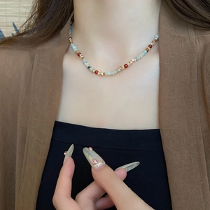 Close-up of a colorful beaded necklace with white, red, and blue stones on a model's neck