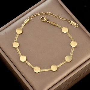 Détail du bracelet chaîne serpent en acier doré avec disques ronds dans son coffret à bijoux