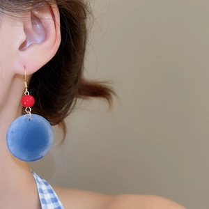 Détail de boucles d'oreilles rétro en acrylique avec perles rouges et disques bleus