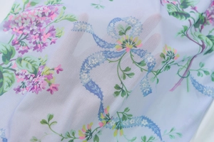 Detail of light blue mesh fabric featuring purple floral prints and breathable texture