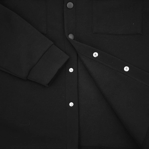 Close-up of black fleece jacket featuring silver metal snap buttons and pocket stitching