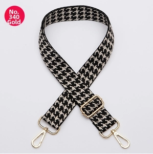 Close-up of black and white houndstooth bag strap with adjustable gold metal buckle