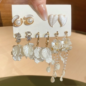 Close-up of five-pair set of pearl and crystal earrings with gold flower accents