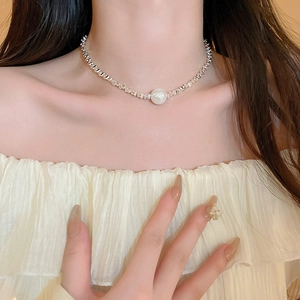 Detail of silver choker necklace with a large white pearl on woman's neck