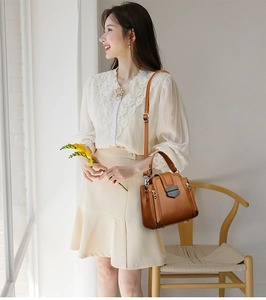 Brown leather crossbody bag with silver buckle and top handle shown on a model