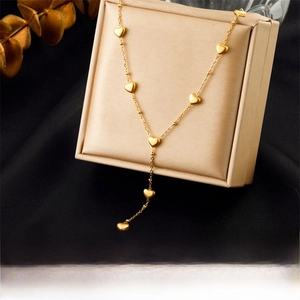 Detailed macro view of gold plated Y-shaped stainless steel necklace with heart pendants