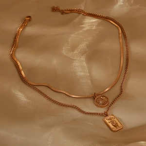 Detail of layered gold celestial necklace with sun moon charms and flower rectangular pendant