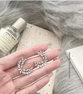 Detail shot of elegant silver leaf earrings with zircon crystals held in hand