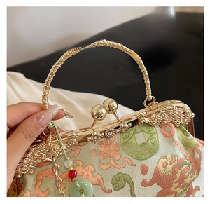 Detailed close-up of Chinese embroidery on green satin bag with golden woven handle