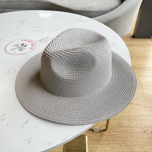 Classic grey woven straw fedora hat for sun protection on a marble table background