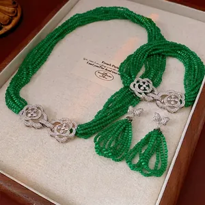 Emerald green beaded necklace and earring set with floral bow accents on velvet