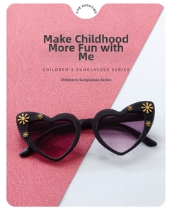 Close-up of heart-shaped kids sunglasses featuring gold flower details and purple lenses