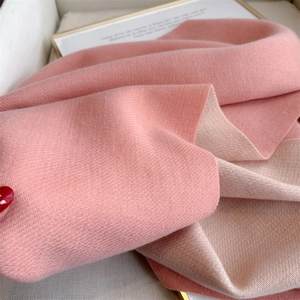 Detail shot of the soft woven texture on a pink and beige double-sided cashmere-like scarf
