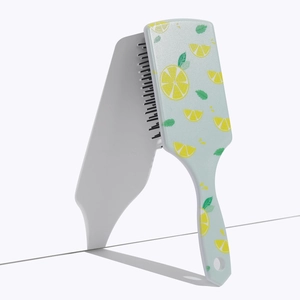 Detail of square air cushion hairbrush with lemon pattern print and light blue handle
