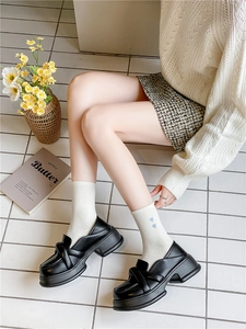 Close-up of white crew socks with blue heart embroidery paired with black loafers