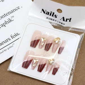 Sparkly cherry red French tip press-on nails with champagne diamonds and heart rhinestones