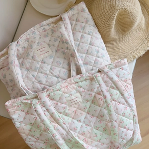 Detail of floral quilted cotton tote bags with French labels and soft padding texture