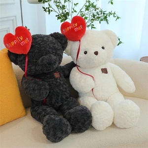 Close-up of black and white plush teddy bears with red heart balloons on a cozy sofa