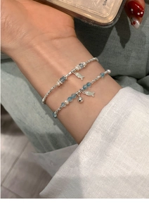 Close-up of beaded bracelets with fish charms and pearls on a woman's wrist