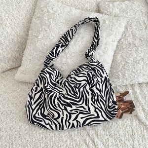 Detail of a large canvas zebra print hobo bag on a soft white plush background