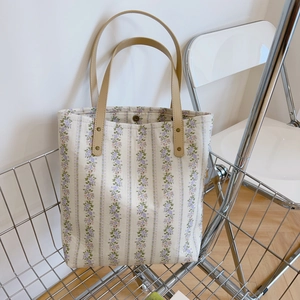 Floral canvas tote bag with purple flower pattern and faux leather handles in metal basket