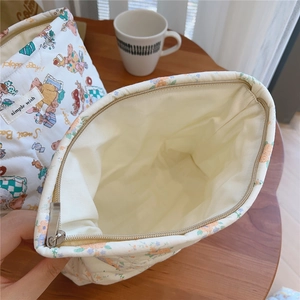 Quilted floral makeup bag with cute bear pattern on wooden desk and yellow inner lining