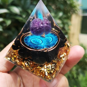 Close-up of Orgone pyramid featuring purple crystal ball and obsidian base with gold foil