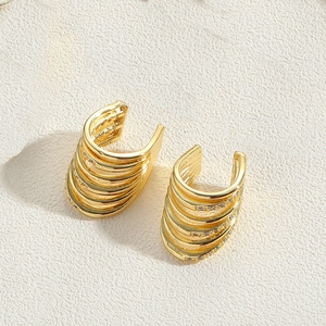 Macro detail of gold-plated multi-layer ear cuff with shimmering zircon accents