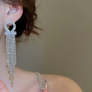 Close-up of geometric silver tassel earrings with sparkling rhinestones on model