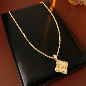 Gros plan d'un pendentif trèfle doré serti de zircons sur un support de bijoux en cuir noir