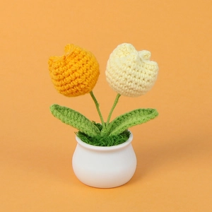 Detail of handmade crochet yellow and white tulips in a white ceramic pot on orange background