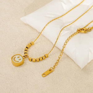 Macro view of gold smile necklace with white enamel square pendant and k18 engraving
