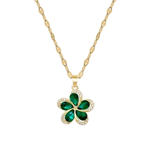 Detail of gold floral necklace featuring green gemstone petals and shimmering crystal borders